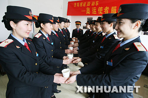  4月10日，动车队乘务员练习为乘客送水礼仪。 当日，铁路济南客运段动车队对北京、上海、青岛方向动车组的80多名列车乘务员，进行站姿、行走、微笑等礼仪培训，用更好的服务迎接北京奥运。 新华社发(吕传泉 摄) 